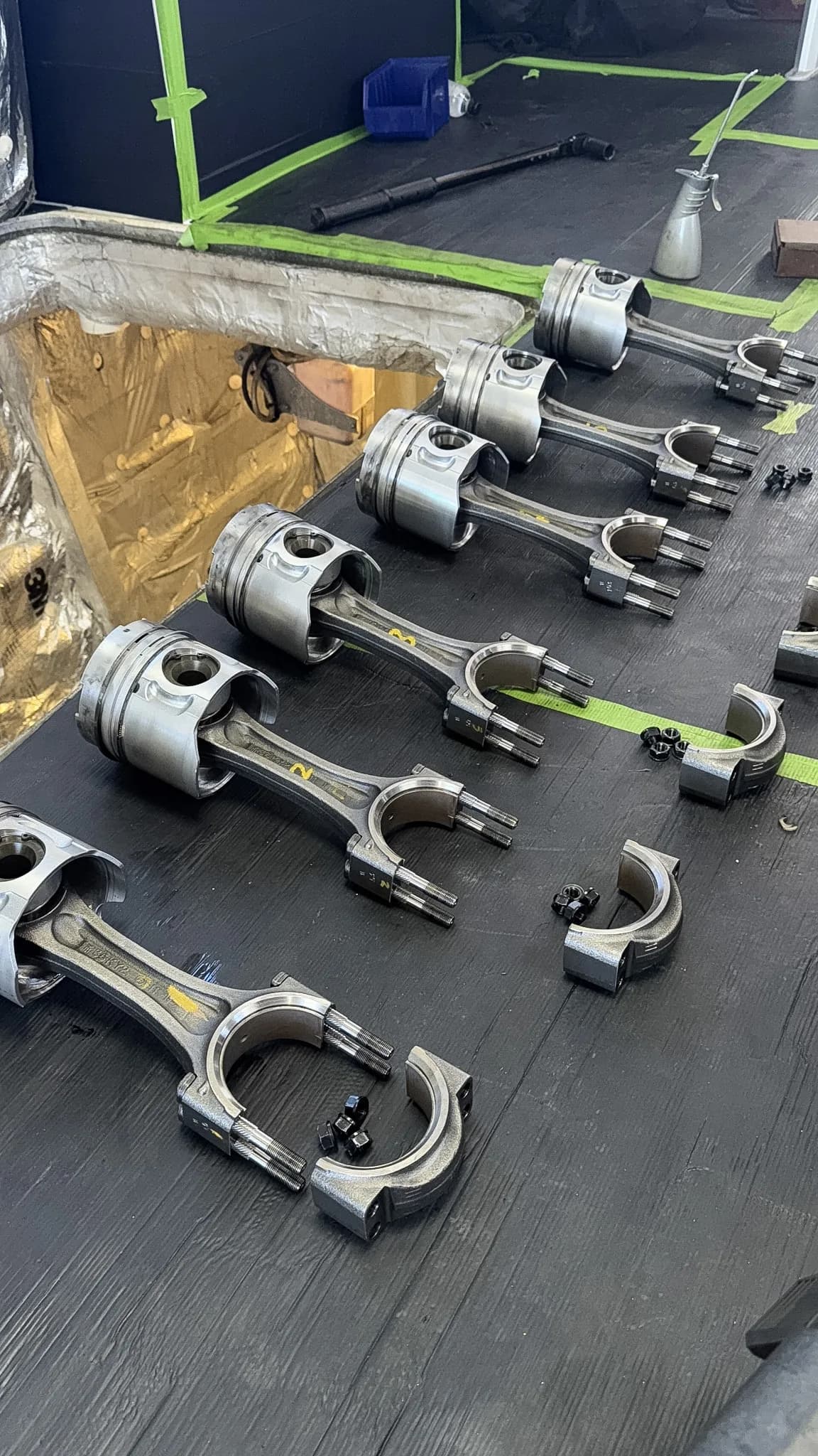 Pistons and connecting rods laid out in order during a Yanmar engine rebuild