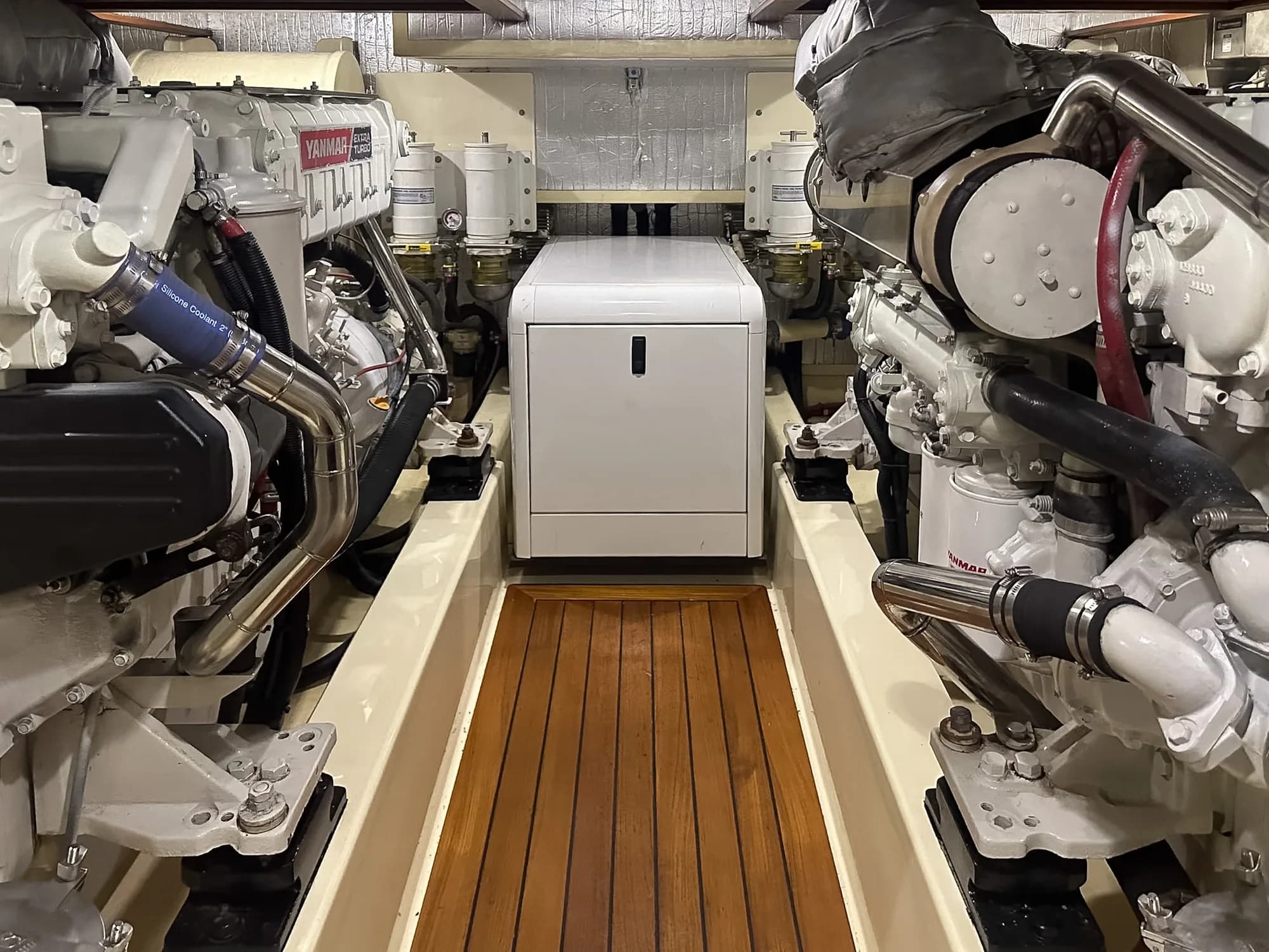 Twin Yanmar marine diesels installed either side of a teak walkway in a boat’s engine bay