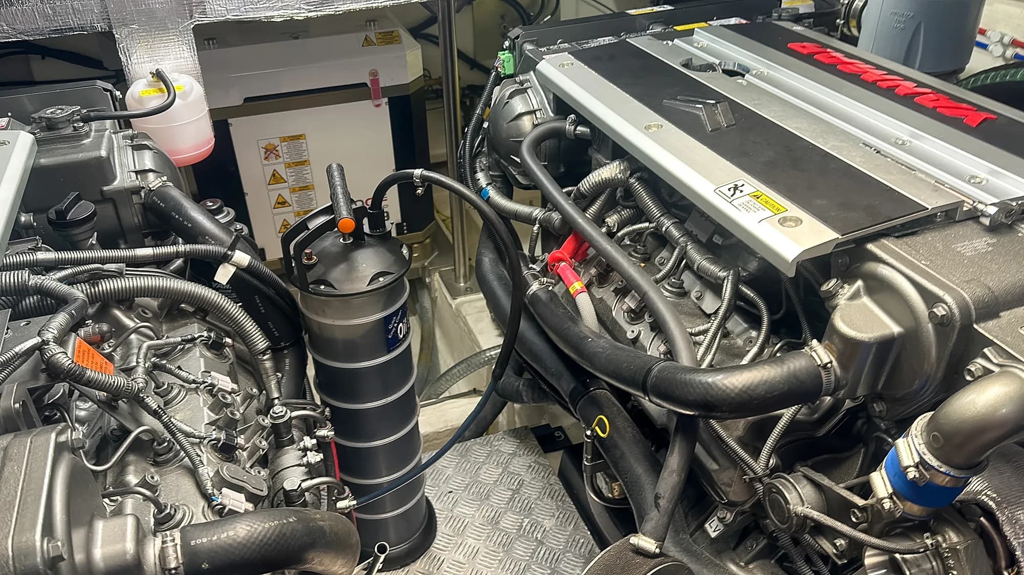 A Yanmar marine diesel being serviced, with an oil extractor pump standing in the engine bay