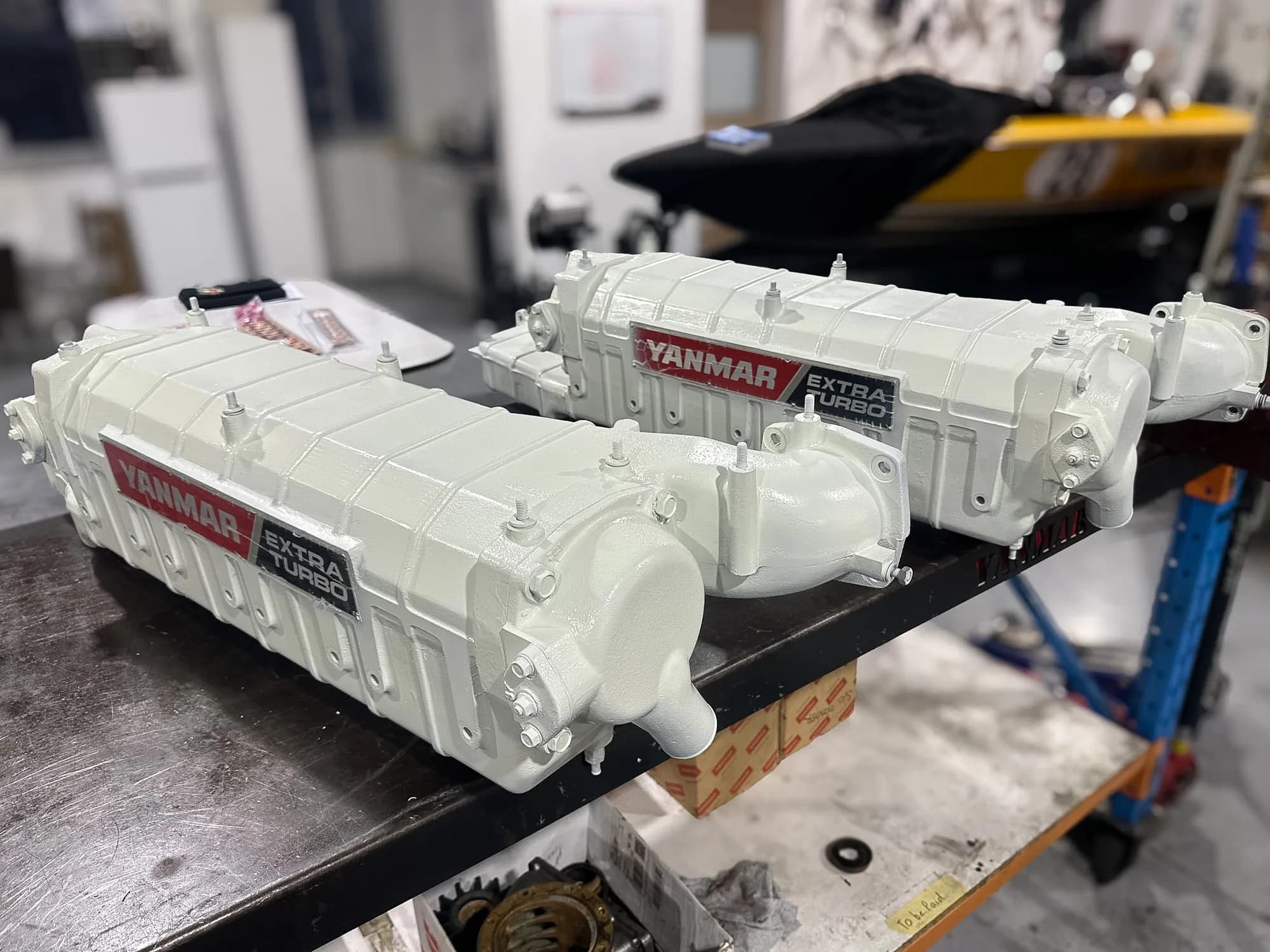Two freshly repainted Yanmar Extra Turbo aftercooler housings on the Sydney Diesel Marine workbench